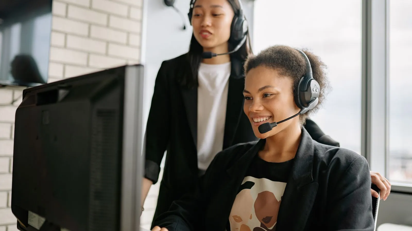 Customer support team with headsets working at computers in an office