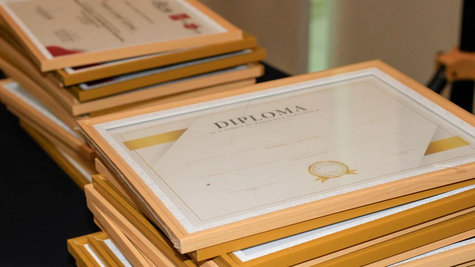Framed diplomas and certificates stacked on a table