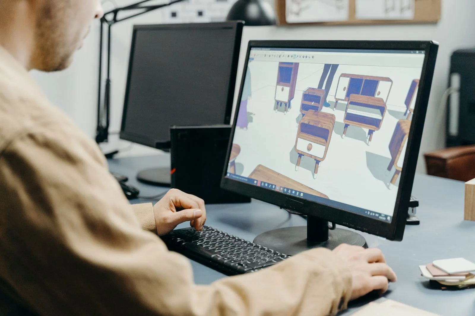A product designer models furniture in 3D CAD software on a desktop monitor