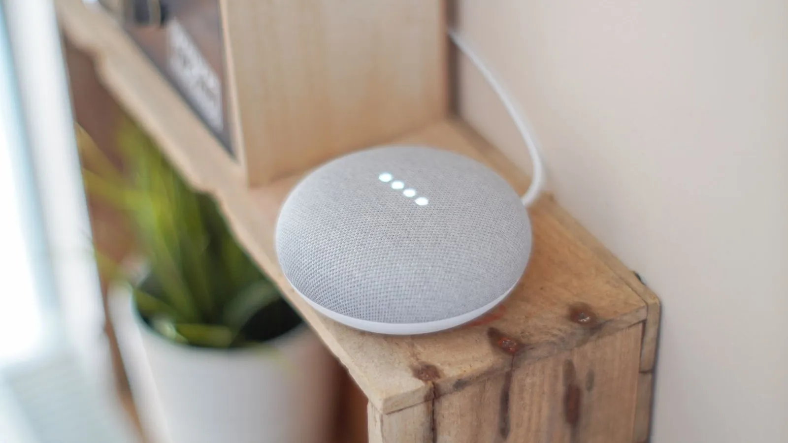 A smart speaker with a voice assistant on a wooden shelf at home
