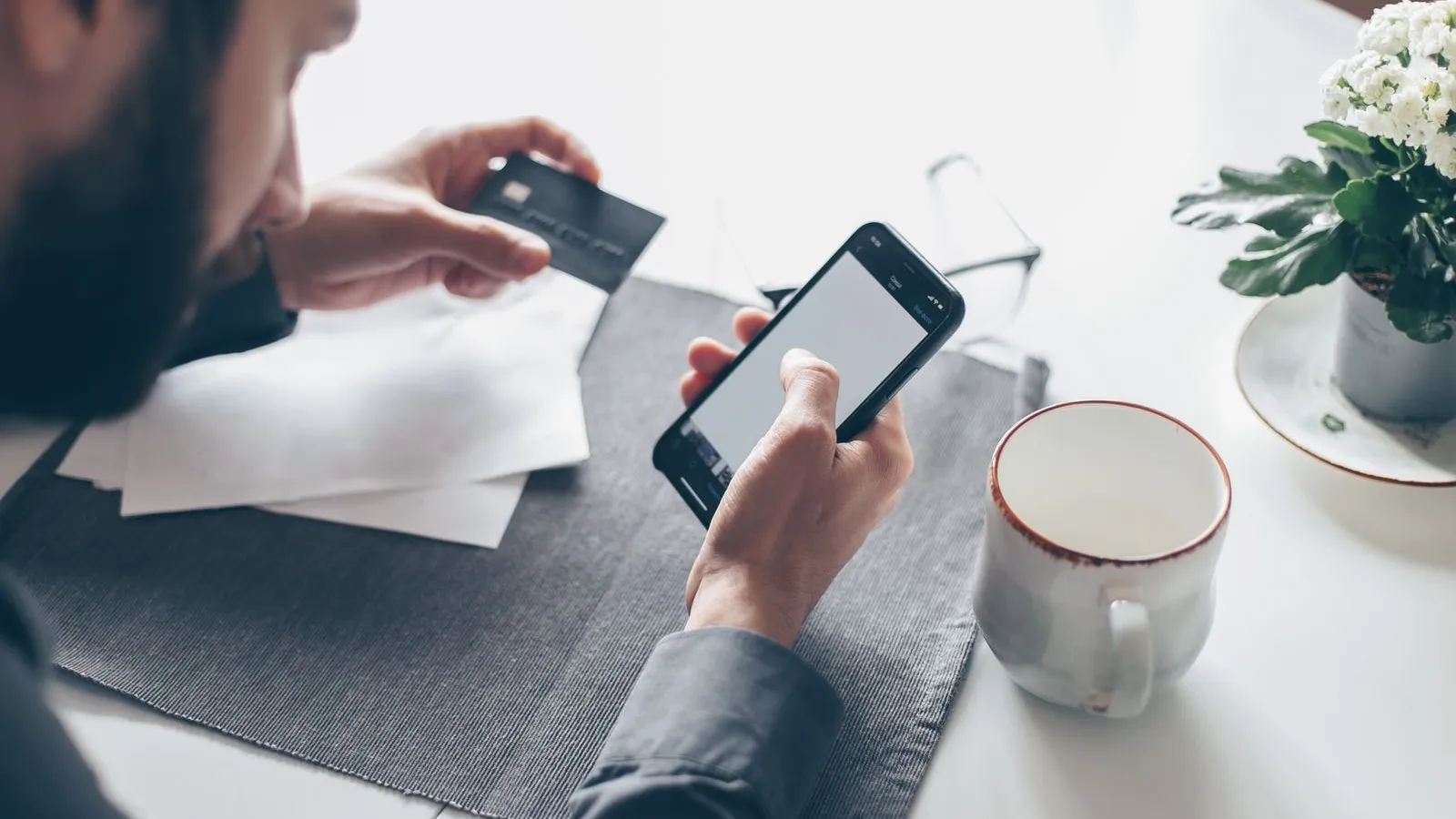 A man checks a banking app on his phone while holding a payment card