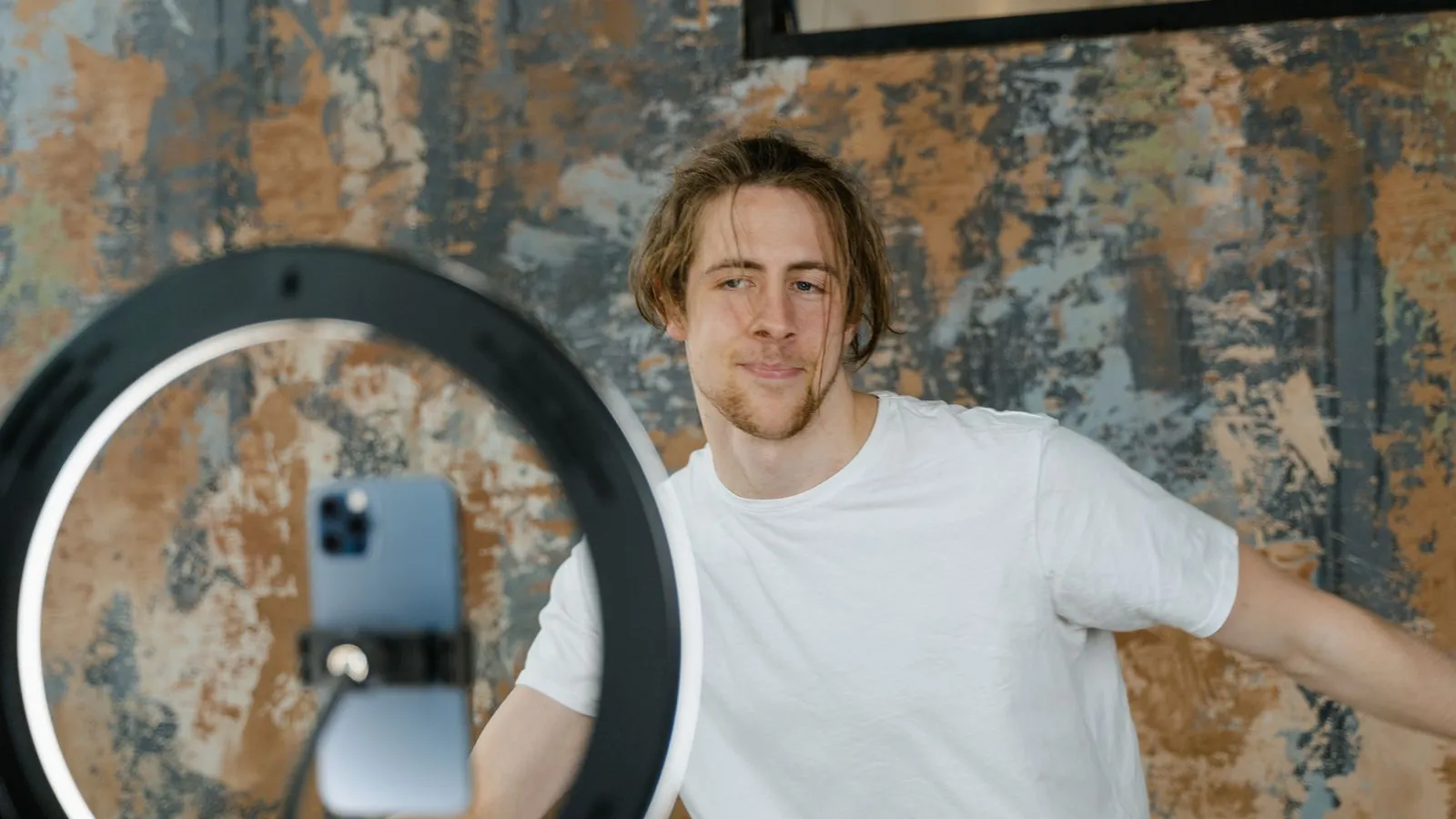 A content creator records a video on a smartphone mounted in a ring light