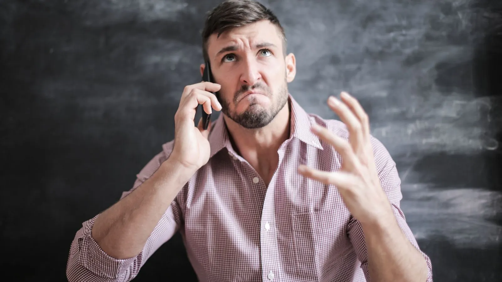 A frustrated man gestures while talking on a phone call