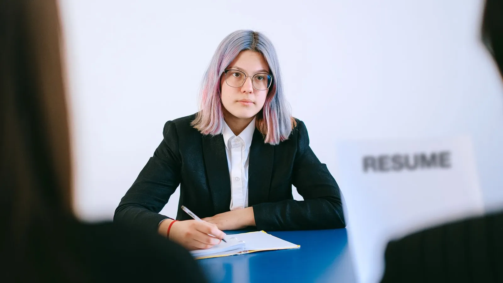 A young job candidate in a suit at an interview, with a resume on the table