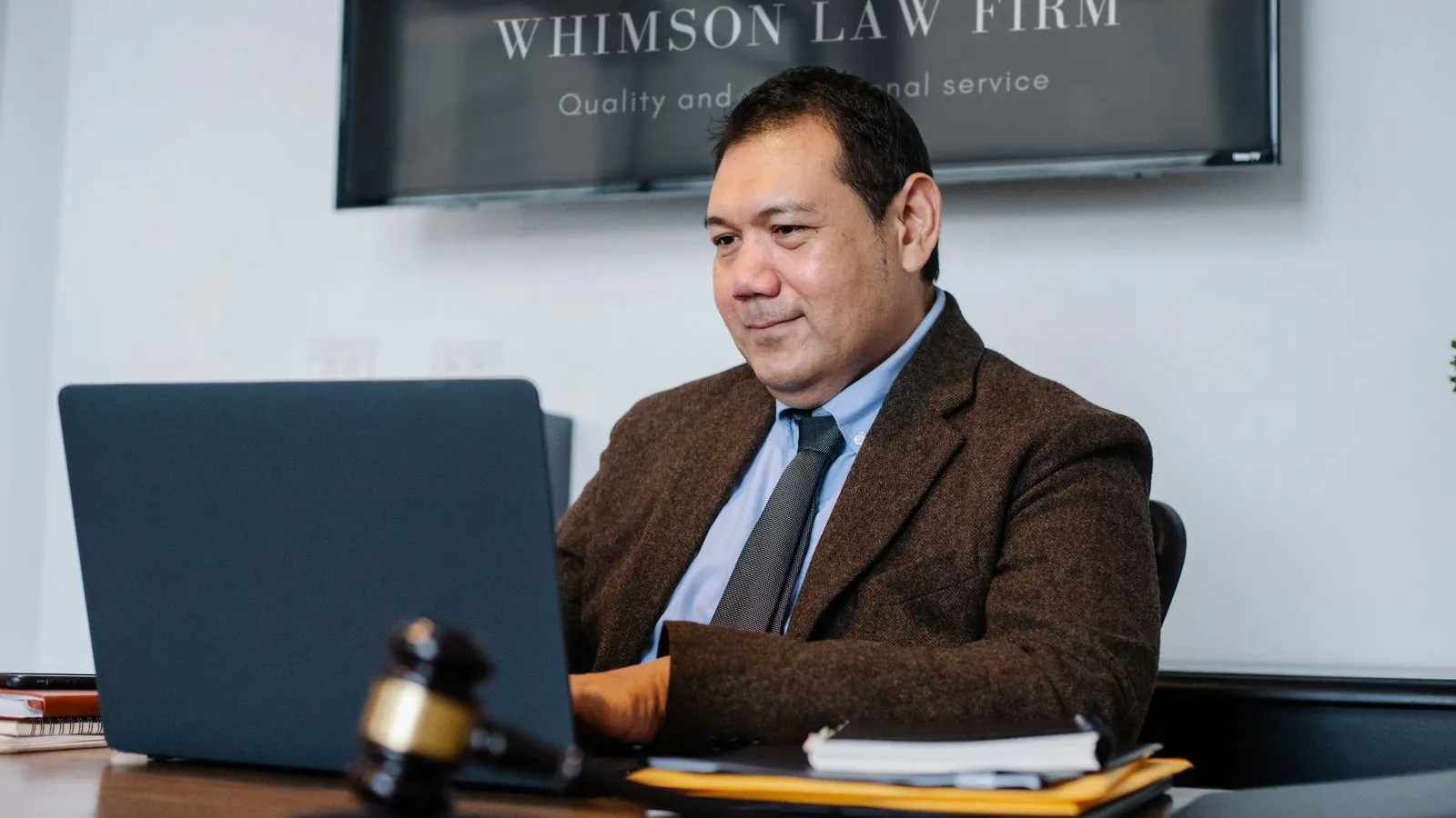 A lawyer working on a laptop at a desk with a gavel in the foreground